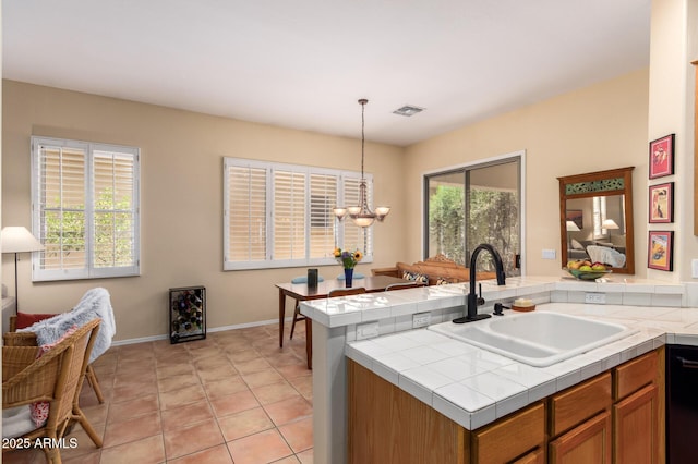 1851 W Periwinkle Way, Chandler, AZ 85248 - kitchen featuring tile countertops, decorative light fixtures, brown cabinetry, black dishwasher, and a peninsula