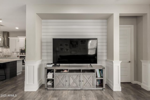 details featuring wall chimney exhaust hood, appliances with stainless steel finishes, and decorative backsplash