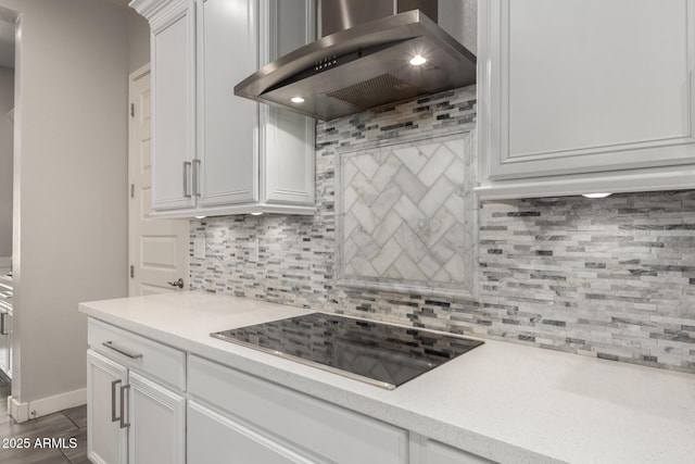 kitchen featuring wall chimney range hood, white cabinets, decorative backsplash, and black electric cooktop