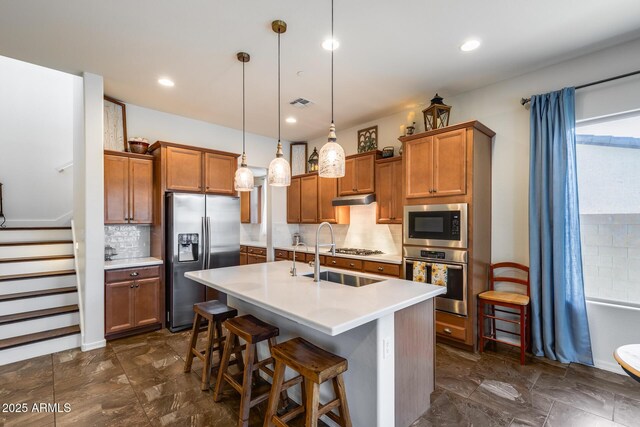 31332 N 137th Ln, Peoria, AZ 85383 - kitchen featuring appliances with stainless steel finishes, brown cabinetry, tasteful backsplash, light countertops, and a kitchen island with sink