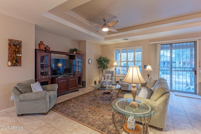 living room with ceiling fan, light tile patterned floors, and a tray ceiling