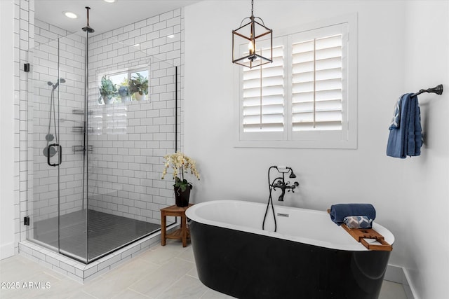 full bath featuring tile patterned flooring, a stall shower, baseboards, and a freestanding tub
