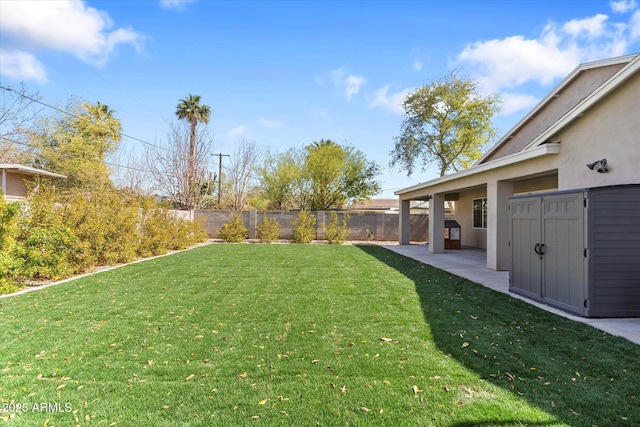 view of yard featuring a patio area, a shed, fence, and an outbuilding