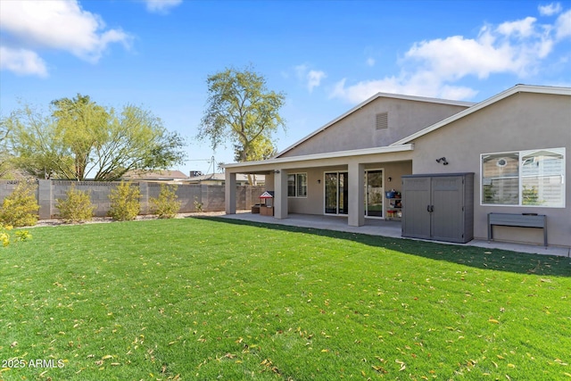rear view of property with a yard, stucco siding, a patio, and fence