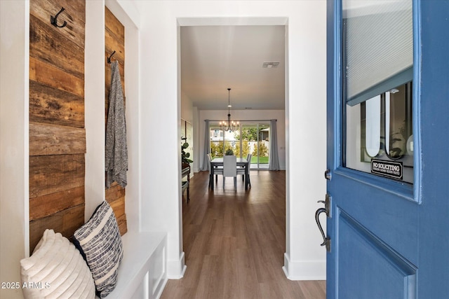 foyer entrance with a chandelier, visible vents, and wood finished floors