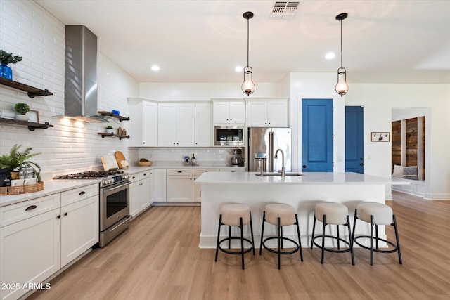 kitchen with a sink, a kitchen breakfast bar, wall chimney range hood, and stainless steel appliances