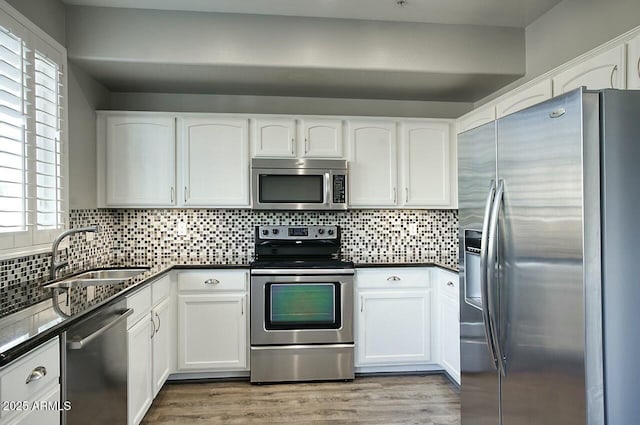 kitchen with a healthy amount of sunlight, white cabinetry, sink, and appliances with stainless steel finishes