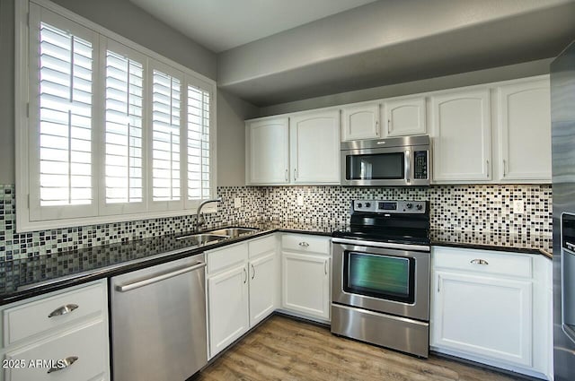 kitchen with white cabinets, sink, stainless steel appliances, and tasteful backsplash