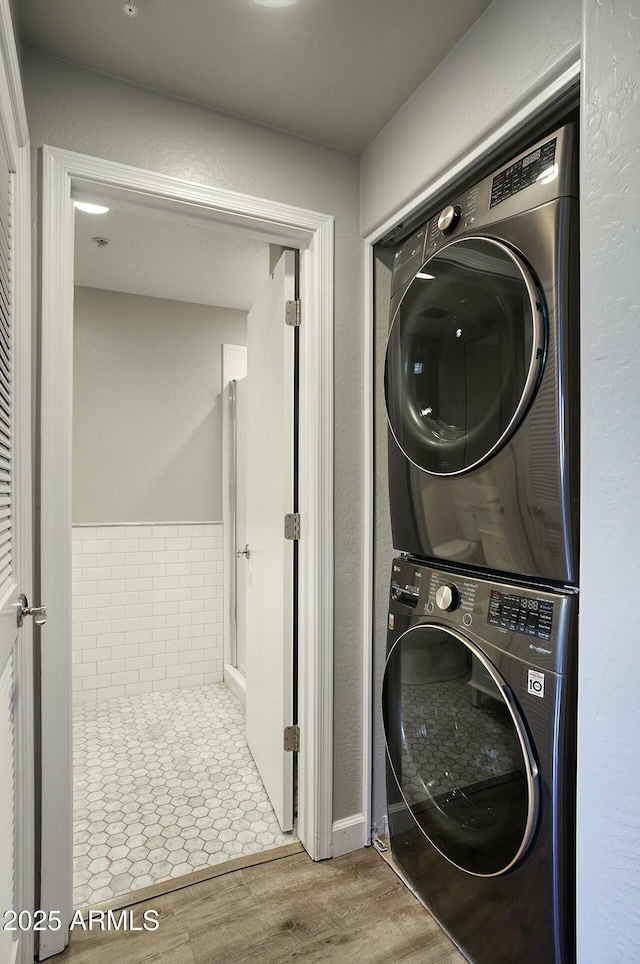 clothes washing area featuring light wood-type flooring and stacked washer / dryer