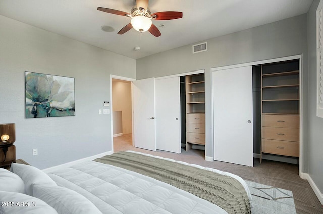 bedroom featuring two closets, light colored carpet, and ceiling fan