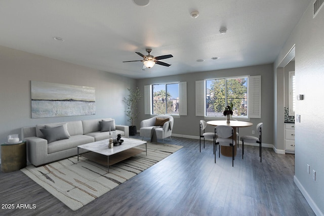 living room with ceiling fan and dark wood-type flooring