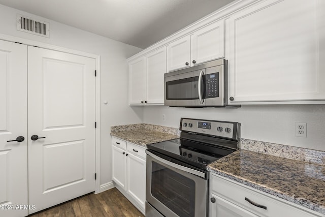 kitchen with white cabinets, appliances with stainless steel finishes, dark wood-type flooring, and dark stone counters