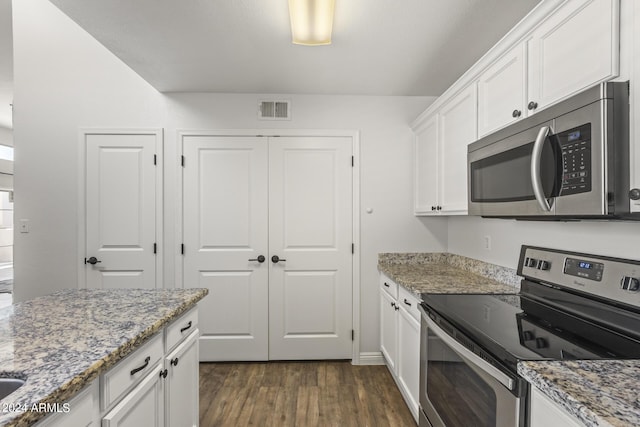 kitchen featuring light stone countertops, white cabinetry, stainless steel appliances, and dark wood-type flooring