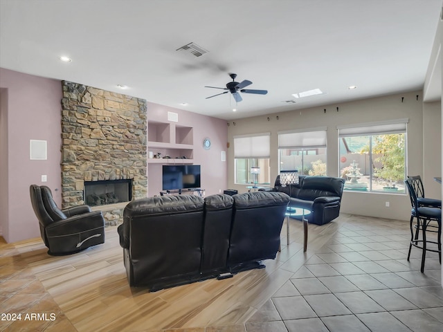 living room with built in shelves, a fireplace, ceiling fan, and light tile patterned floors