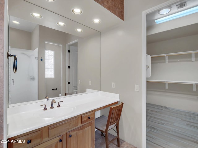 bathroom with walk in shower, vanity, and hardwood / wood-style flooring