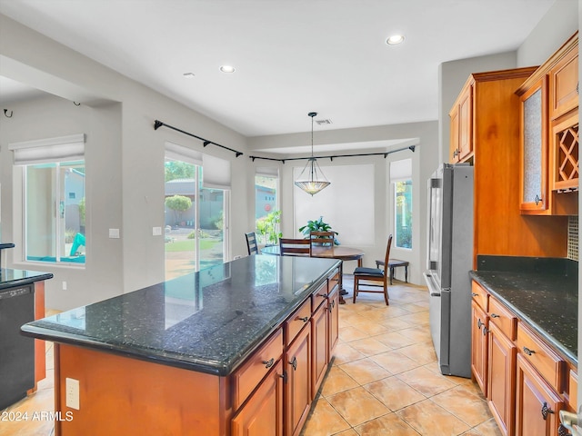 kitchen featuring a center island, dishwasher, pendant lighting, dark stone countertops, and stainless steel fridge