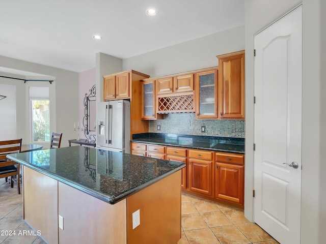 kitchen featuring dark stone counters, a barn door, light tile patterned floors, stainless steel fridge with ice dispenser, and a kitchen island