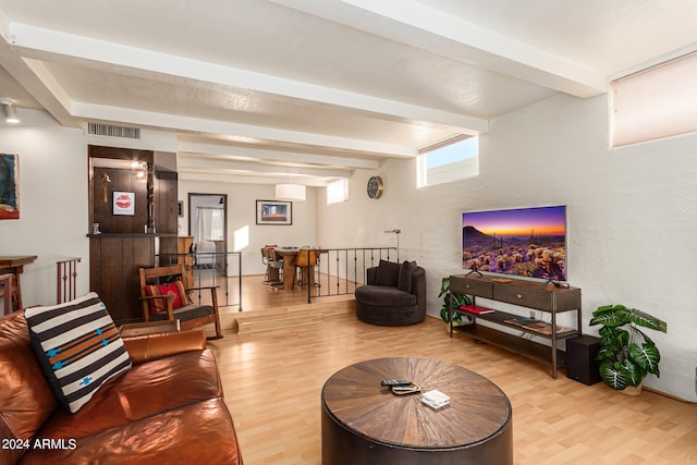 living room featuring beam ceiling, light hardwood / wood-style flooring, and a wall unit AC