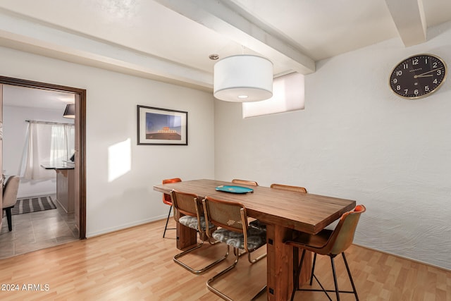 dining room featuring beamed ceiling and light wood-type flooring