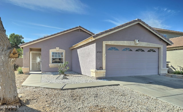 ranch-style house with driveway, an attached garage, and stucco siding