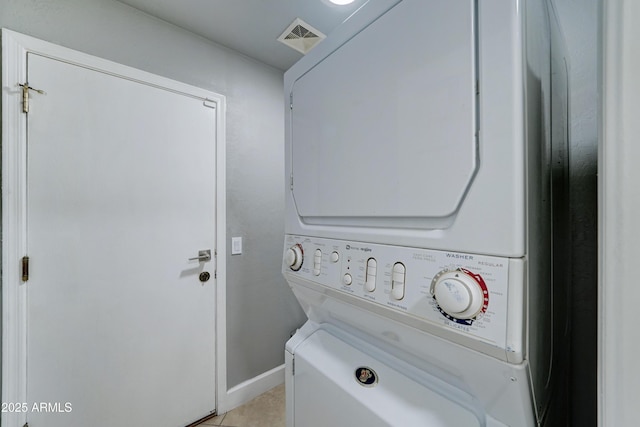 laundry room with light tile patterned flooring, visible vents, and stacked washer and clothes dryer