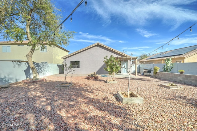 rear view of property featuring a fenced backyard and stucco siding