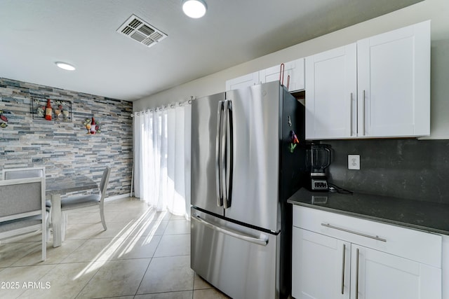 kitchen featuring dark countertops, light tile patterned floors, white cabinets, and freestanding refrigerator