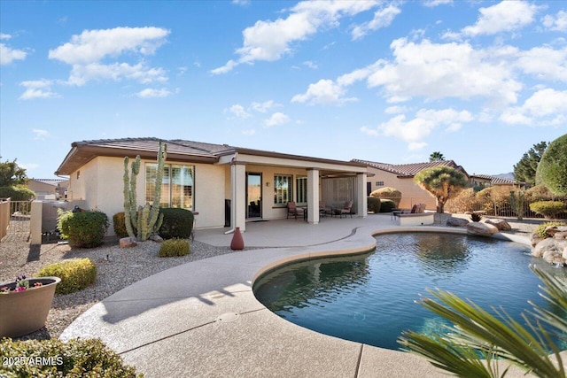 back of property with a fenced in pool and a patio