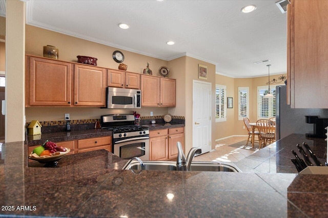 kitchen with crown molding, sink, decorative light fixtures, and appliances with stainless steel finishes