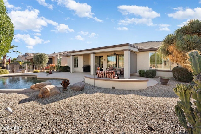 rear view of property featuring a fenced in pool and a patio area