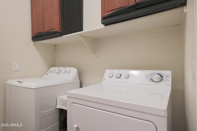 clothes washing area with washer and clothes dryer and cabinets