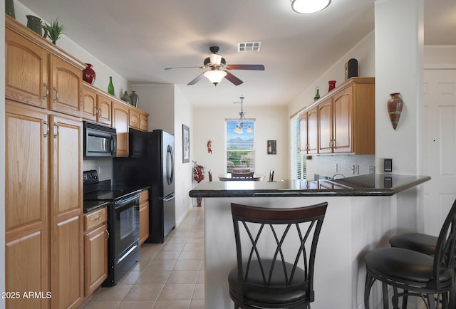 kitchen with kitchen peninsula, a kitchen bar, black appliances, light tile patterned floors, and pendant lighting