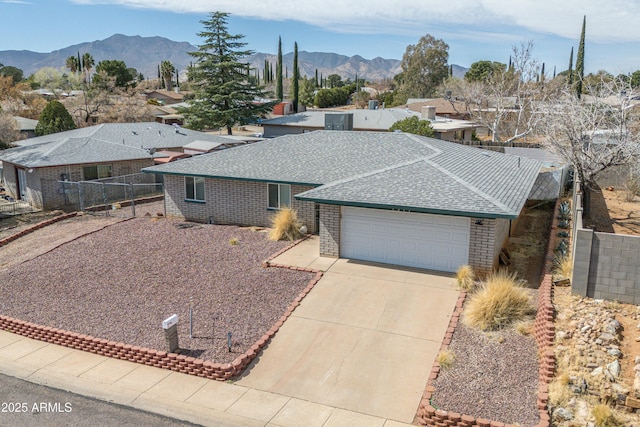 view of front of home featuring a shingled roof, concrete driveway, an attached garage, a mountain view, and brick siding