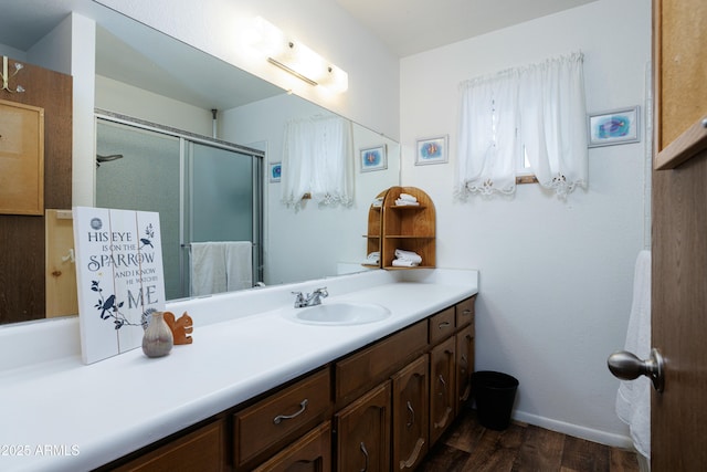 bathroom featuring baseboards, vanity, a shower stall, and wood finished floors