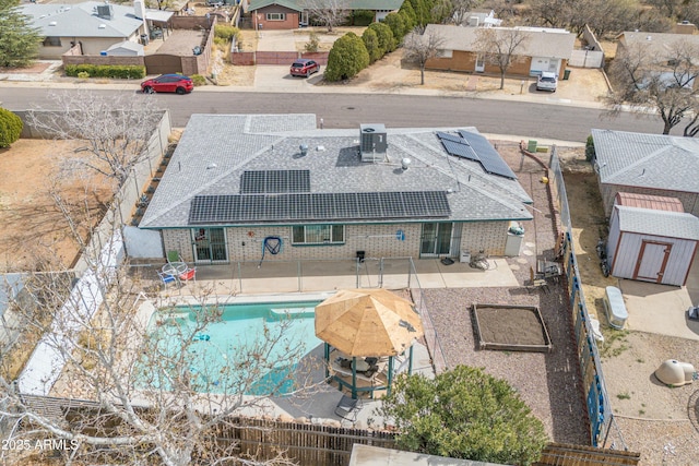 view of swimming pool featuring a patio, a fenced backyard, a residential view, an outdoor structure, and a shed