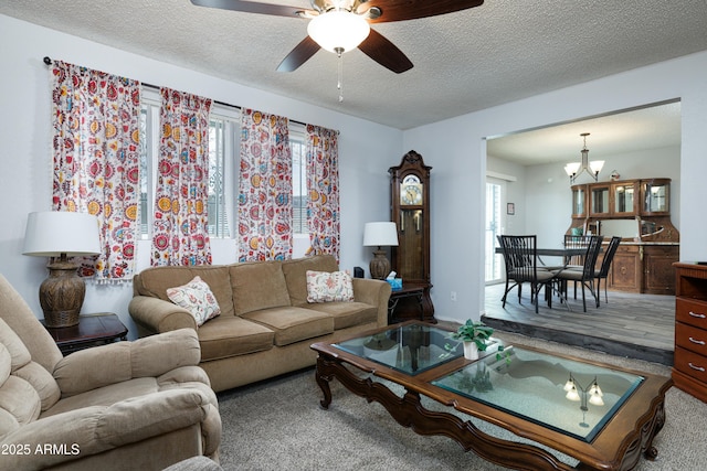 carpeted living room with a textured ceiling and ceiling fan with notable chandelier