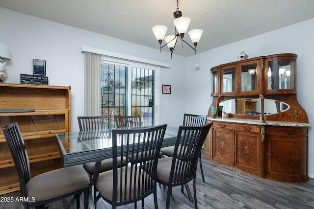 dining space with a textured ceiling, wood finished floors, and an inviting chandelier