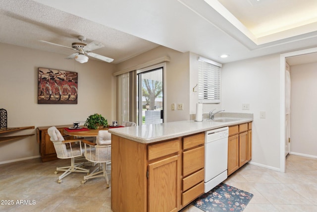 kitchen with a sink, light countertops, baseboards, and dishwasher