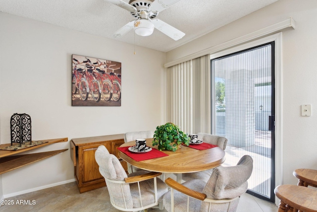 dining area with baseboards, a ceiling fan, and a textured ceiling