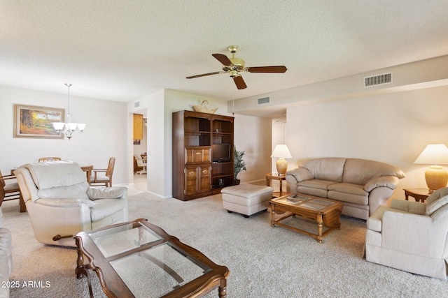 living room with visible vents, a textured ceiling, ceiling fan with notable chandelier, and light carpet