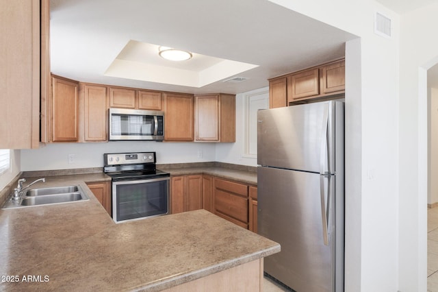 925 S Longmore Unit 201, Mesa, AZ 85202 - kitchen featuring stainless steel appliances, a sink, a raised ceiling, a peninsula, and brown cabinets