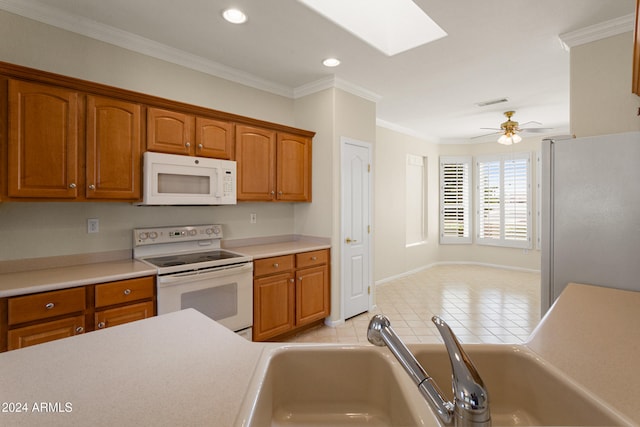 kitchen with white appliances, a skylight, light tile patterned floors, crown molding, and ceiling fan