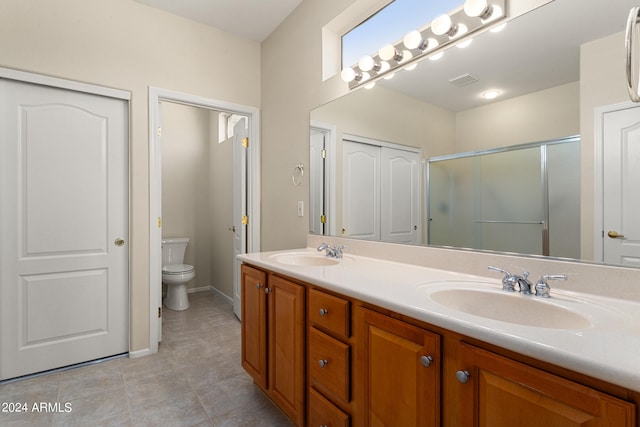 bathroom featuring tile patterned flooring, vanity, toilet, and an enclosed shower