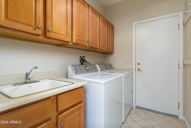 laundry area featuring washer and clothes dryer, sink, light tile patterned floors, and cabinets