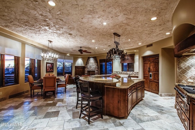 kitchen featuring light stone counters, a large island, decorative light fixtures, and tasteful backsplash