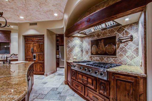 kitchen with appliances with stainless steel finishes, sink, decorative backsplash, custom exhaust hood, and light stone countertops