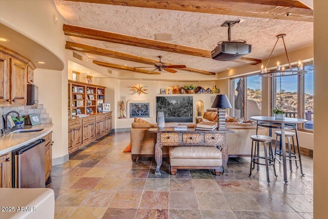 living room with ceiling fan, beam ceiling, sink, and a textured ceiling