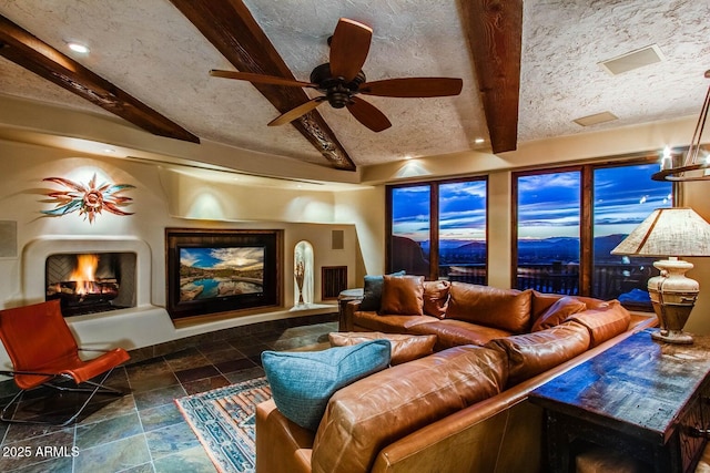 living room with ceiling fan, vaulted ceiling with beams, and a textured ceiling