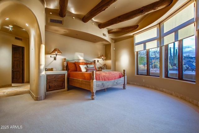 bedroom with light colored carpet and beam ceiling