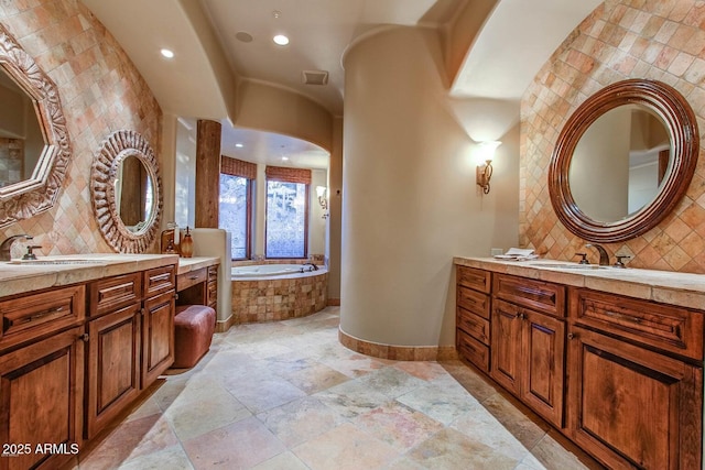 bathroom featuring tiled tub, vanity, and backsplash